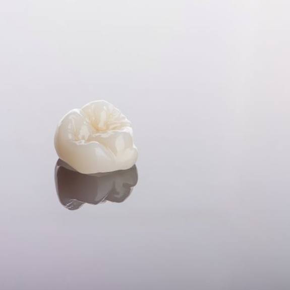 Ceramic dental crown on reflective surface