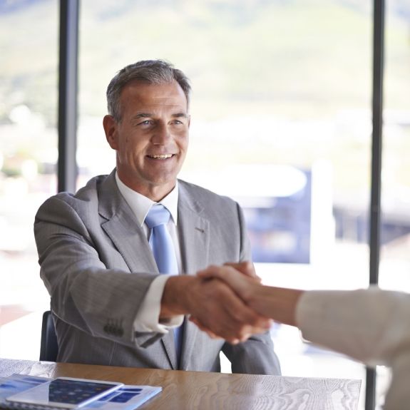 Dental patient shaking hands with dentist after discussing the cost of dental implants