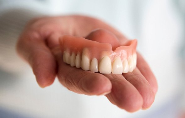 A hand holding a removable upper denture