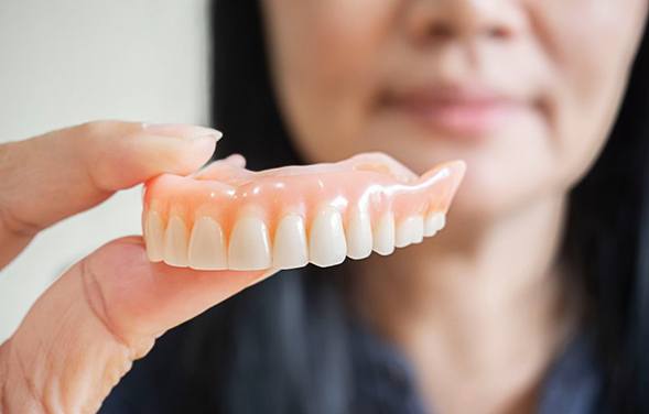 a person holding a set of dentures