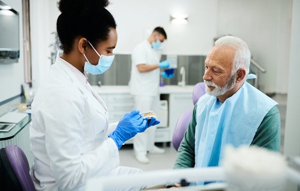 a dentist showing a patient a model of dentures