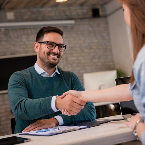 Smiling man shaking hands with emergency dentist