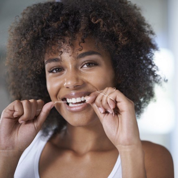 Woman flossing to prevent dental emergencies