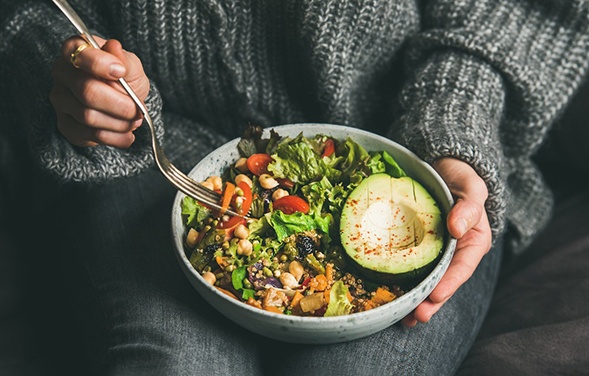 A vegetarian dinner bowl being eaten by a woman