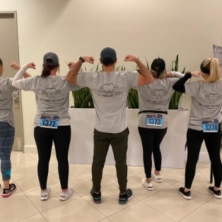 Tulsa dental team members in matching shirts flexing their arms