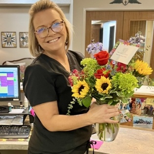 Dental team member in Tulsa holding vase full of flowers