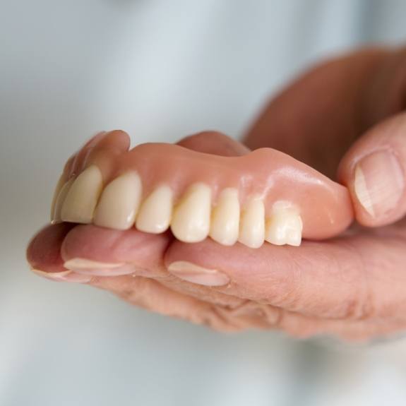 Hand holding full denture