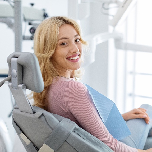 Woman smiling at camera while sitting in dental treatment chair