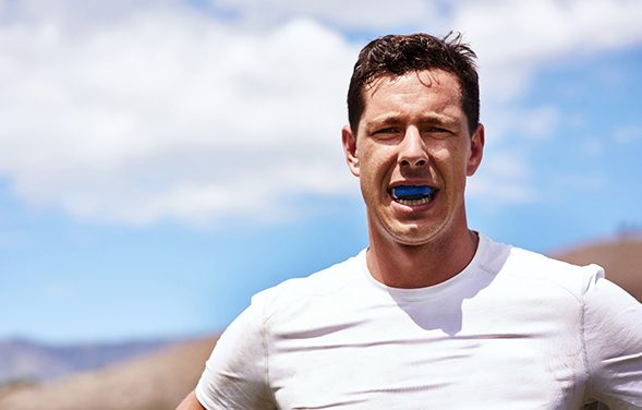 Man smiling while wearing blue mouthguard on hike