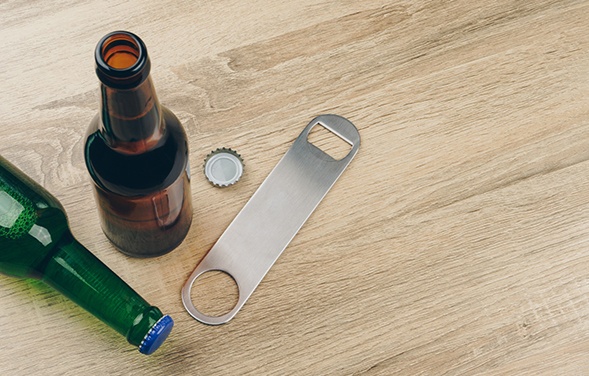 Two bottles on table with bottle cap opener