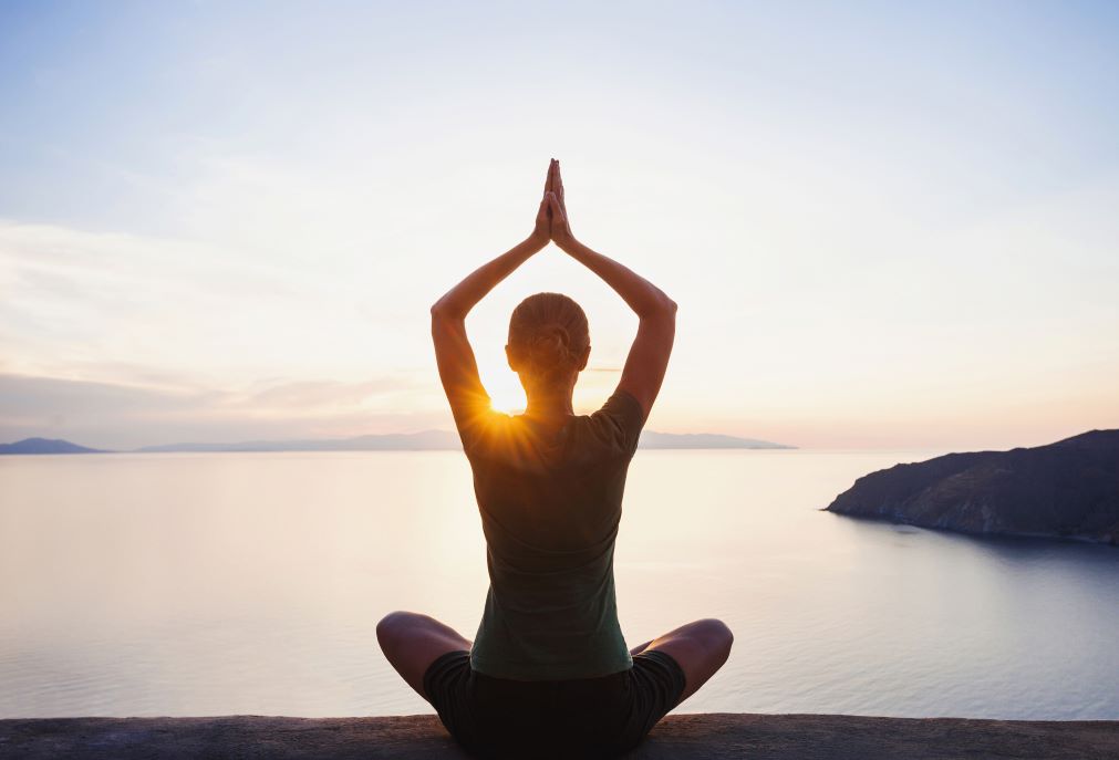 A woman practicing yoga by a lake