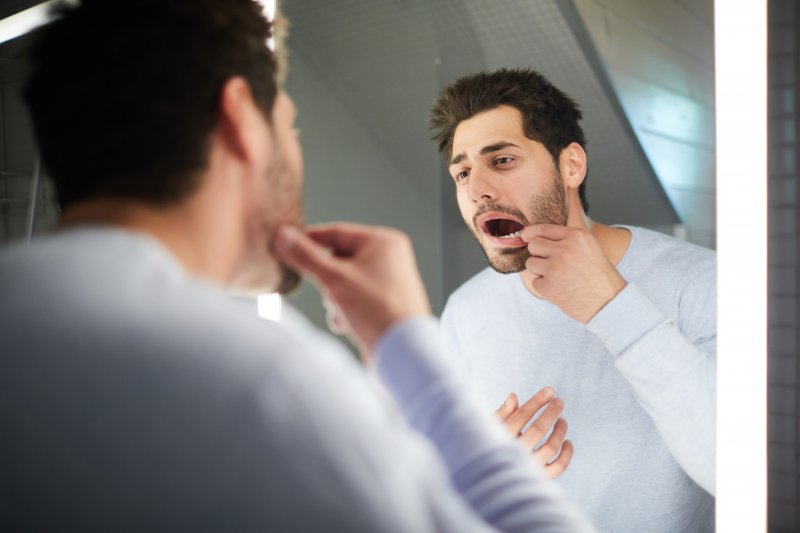 Patient checking for oral cancer in their bathroom mirror