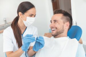 Dentist holding clear aligner smiling at patient.